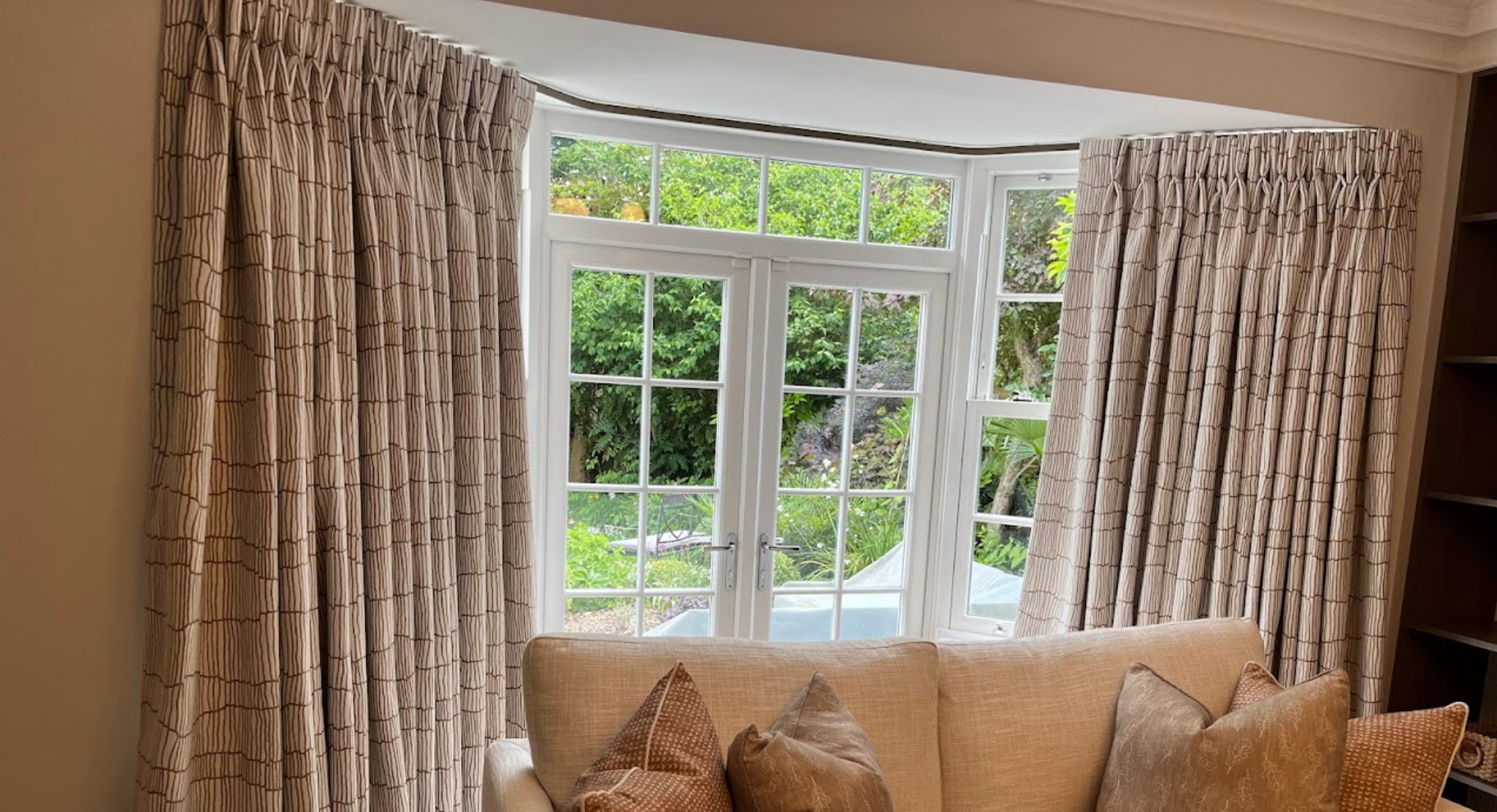 Bespoke interlined bay window curtains with bent-on-site track and French doors, Reading Berkshire family living room by Stripe Interiors